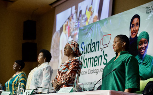 Women standing in front of screen and banner